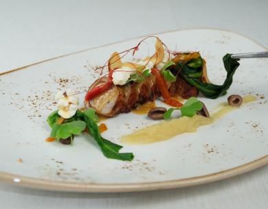 Piatto gourmet con carne, verdure e guarnizioni eleganti.
