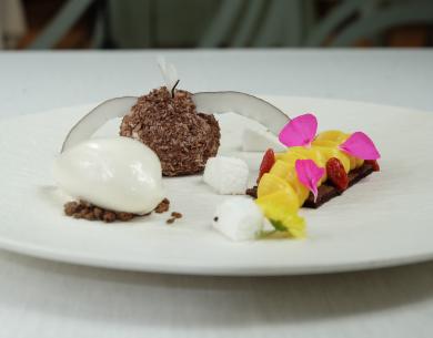 Dessert elegante con cocco, mango e petali di fiori.
