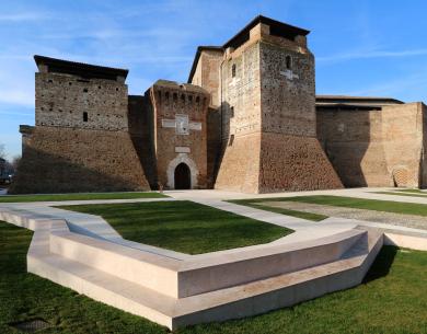 Antica fortezza con mura in mattoni e cortile verde.
