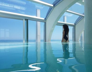 Femme dans une piscine intérieure avec vue sur la mer.