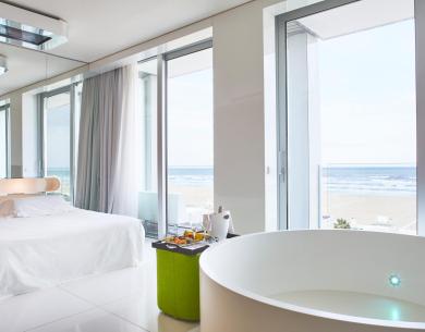 Camera moderna con vista mare, letto e vasca.
