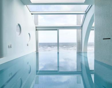 Piscina interna con vista sull'oceano e ampie finestre.