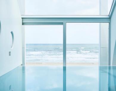 Innenpool mit Meerblick durch große Fenster.