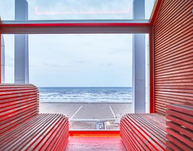 Vista mare da una sauna moderna con legno e luci rosse.