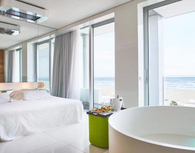 Camera moderna con vista mare, vasca e letto.