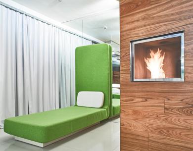 Sala moderna con chaise longue verde e camino.