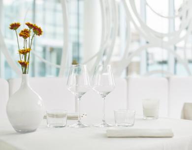 Tavolo elegante con bicchieri, vaso e fiori in un ristorante moderno.