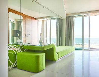 Moderno soggiorno con vista mare e arredamento verde brillante.