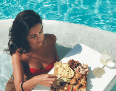 Femme dans la piscine avec table flottante et nourriture.