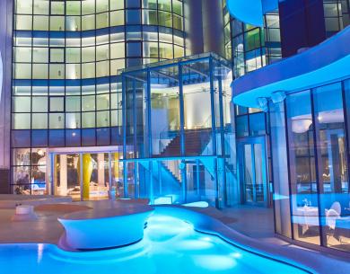 Edificio moderno illuminato di notte con piscina e vetrate curve.