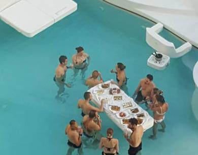 Menschen essen und trinken in einem Pool mit einem schwimmenden Tisch.
