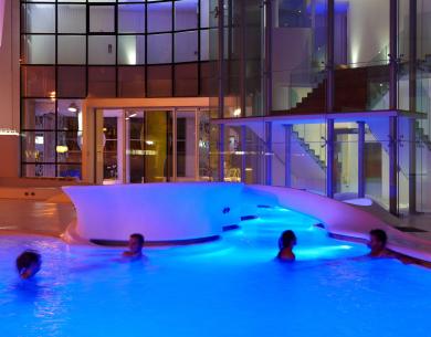 Beleuchteter Pool bei Nacht mit schwimmenden Personen.