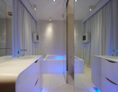 Salle de bain moderne avec éclairage bleu et meubles blancs élégants.