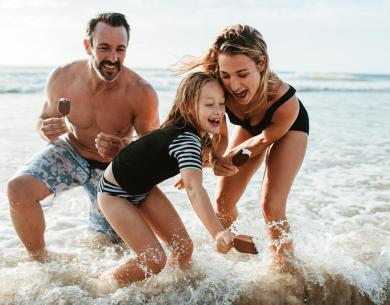 Famille heureuse joue dans la mer avec des glaces, sourires et éclaboussures.
