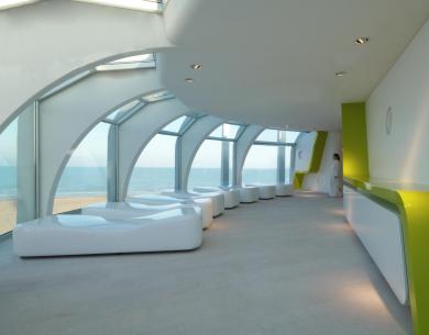 Moderno interno con vista mare, arredi bianchi e dettagli verdi.