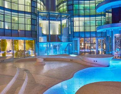 Futuristic illuminated pool with modern glass building.