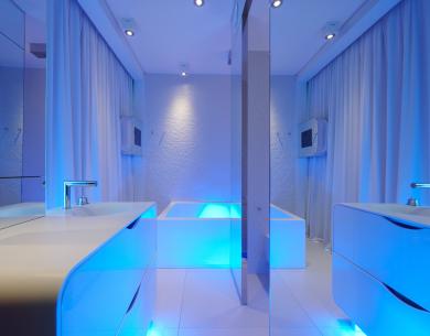 Bagno moderno con illuminazione blu, lavabo e vasca.