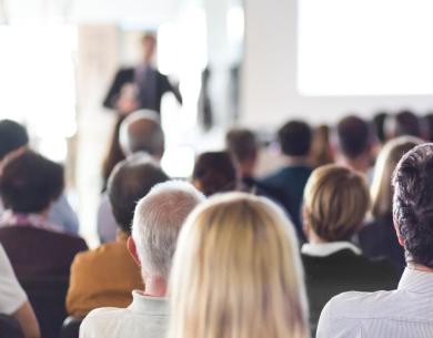 Persone sedute ascoltano una presentazione in una sala conferenze.