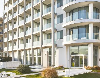 Edificio moderno con balconi curvi e giardino.