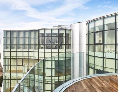 Edificio moderno con ampie vetrate e vista su una terrazza.