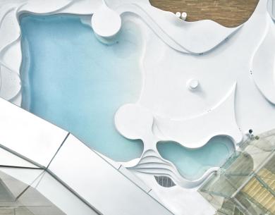 Piscina moderna con design ondulato e strutture in vetro.