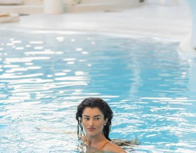 Donna nuota in piscina con acqua limpida.