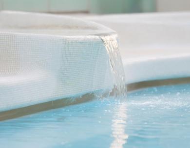 Pool with water cascade in a modern setting.