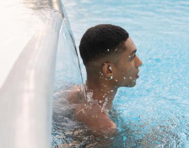 Person im Pool unter einem Wasserfall.