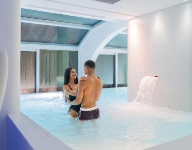 Glückliches Paar im Innenpool mit Wasserfall.