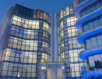 Modernes Gebäude mit Glasfassaden und blauen Lichtern bei Nacht.