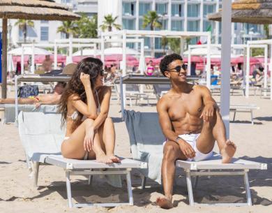 Glückliches Paar sonnt sich auf Strandliegen, sommerliche Stimmung und entspannte Atmosphäre.