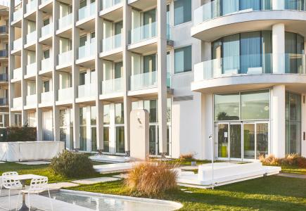 Moderno edificio residenziale con balconi e giardino ben curato.