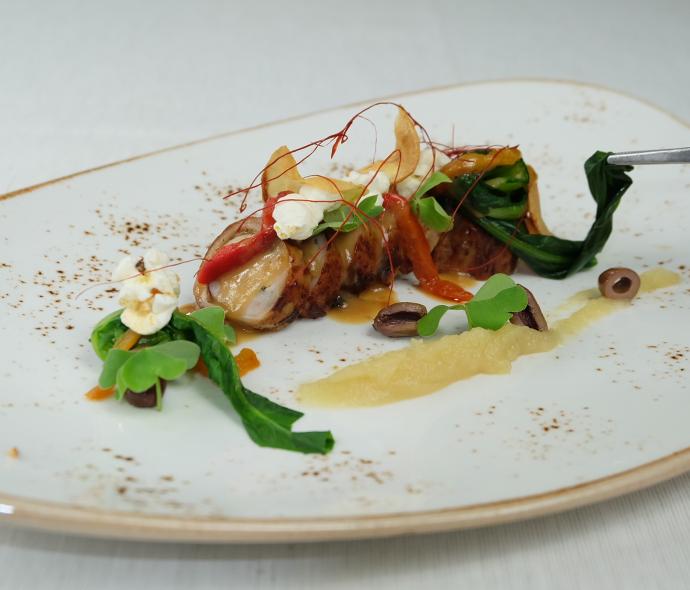 Piatto gourmet con carne, verdure e guarnizioni eleganti.