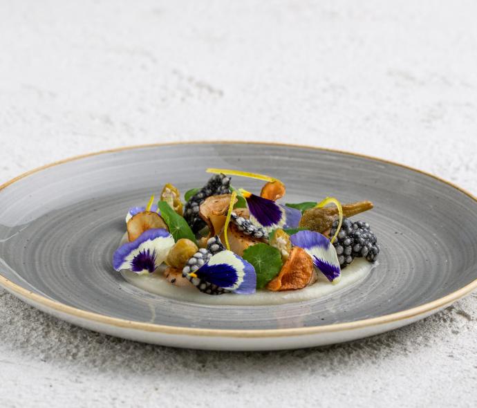 Piatto gourmet con fiori commestibili e ingredienti raffinati.