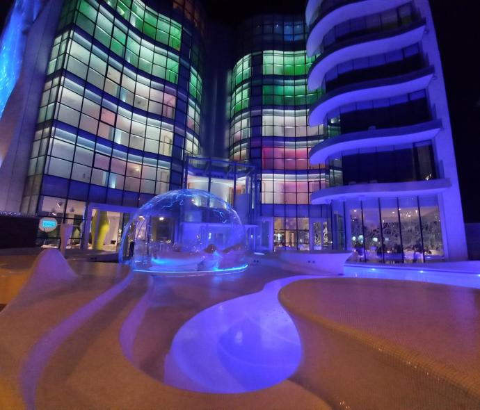 Edificio moderno illuminato di notte con piscina e cupola di vetro.