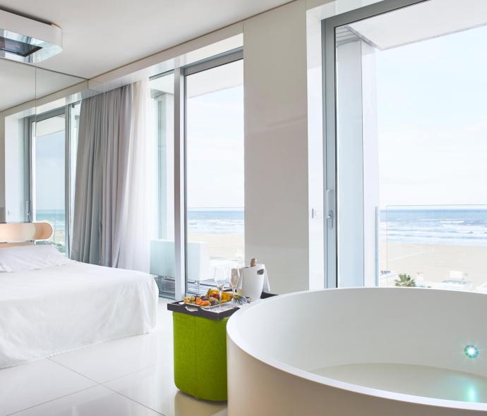 Camera moderna con vista mare, letto e vasca.