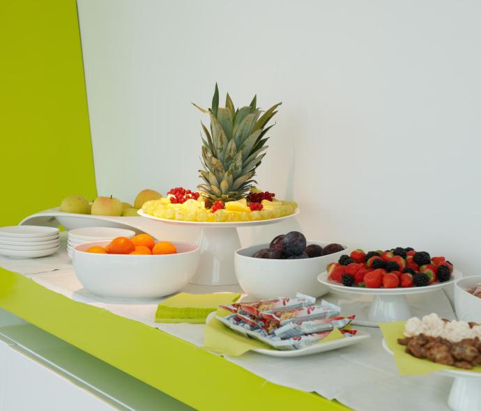 Buffet with fresh fruit, snacks, and various sweets on a white table.