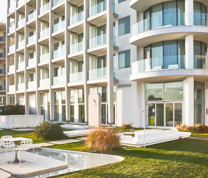 Moderno edificio residenziale con balconi e giardino ben curato.