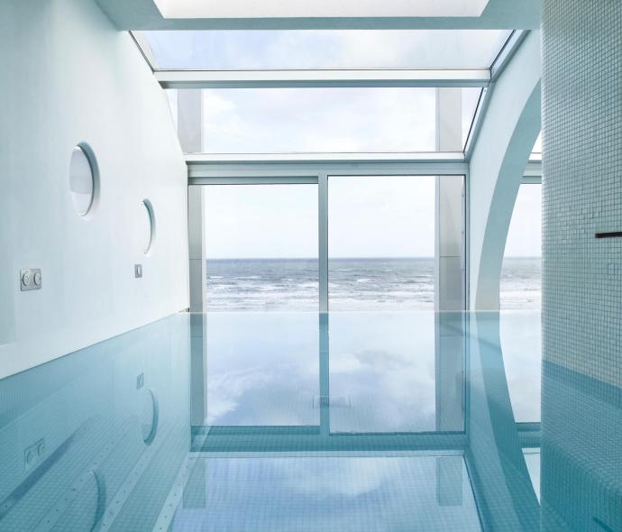 Piscina interna con vista sull'oceano e ampie finestre.