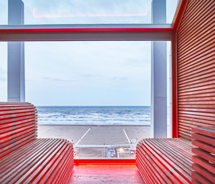 Vista mare da una sauna moderna con legno e luci rosse.