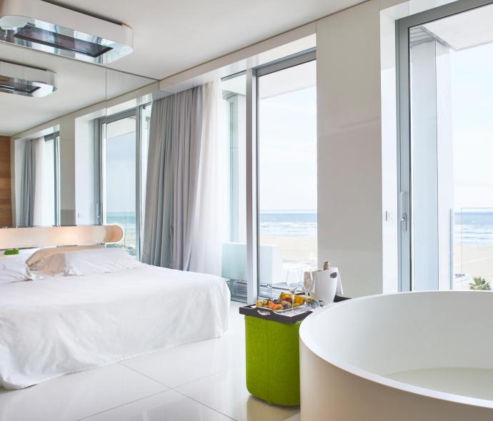 Camera moderna con vista mare, vasca e letto.