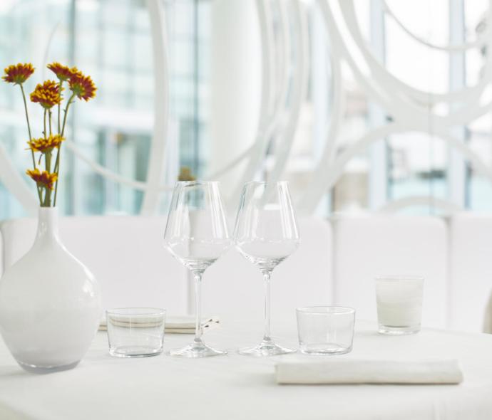 Tavolo elegante con bicchieri, vaso e fiori in un ristorante moderno.