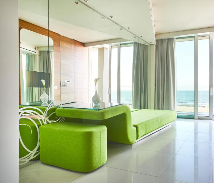 Moderno soggiorno con vista mare e arredamento verde brillante.