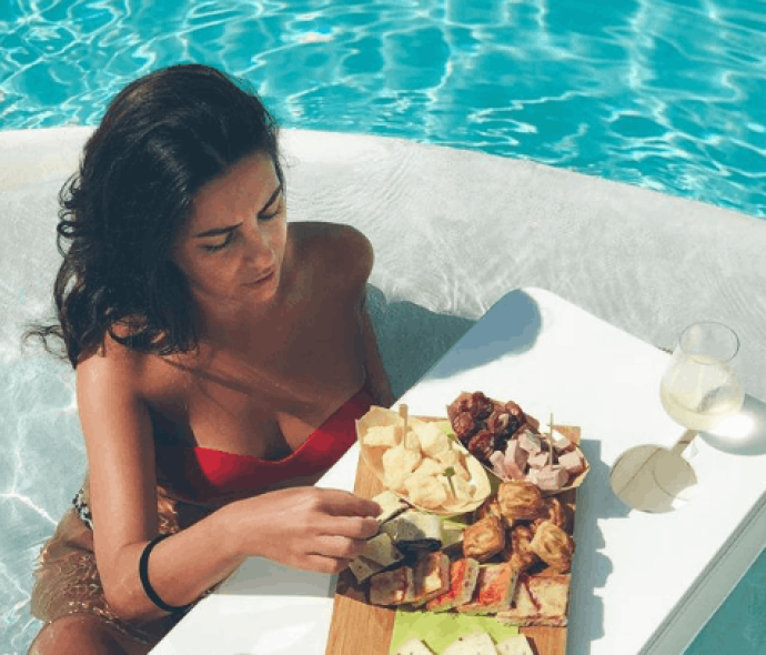 Femme dans la piscine avec table flottante et nourriture.