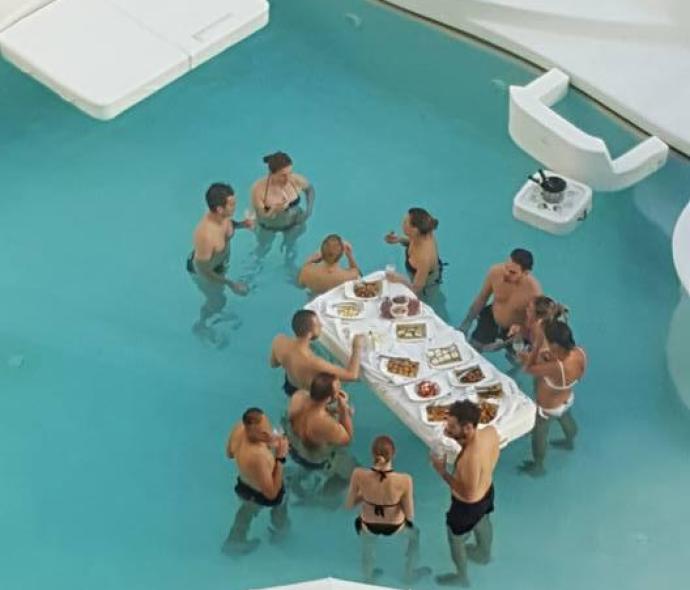 Menschen essen und trinken in einem Pool mit einem schwimmenden Tisch.