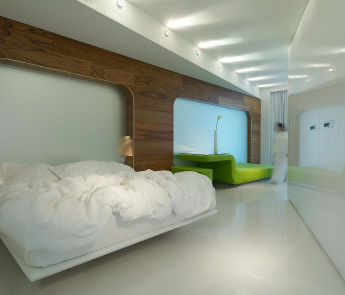 Chambre moderne avec lit blanc et canapé vert.