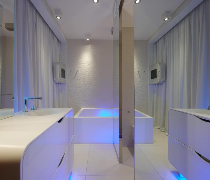 Salle de bain moderne avec éclairage bleu et meubles blancs élégants.