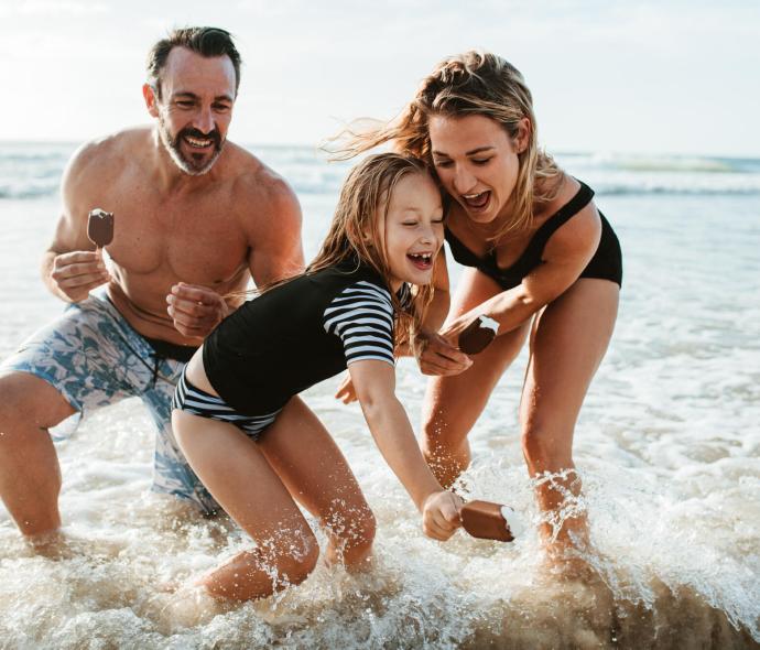 Famille heureuse joue dans la mer avec des glaces, sourires et éclaboussures.