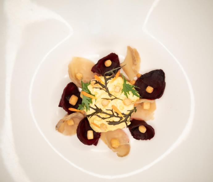 Piatto gourmet con verdure e crema decorativa.