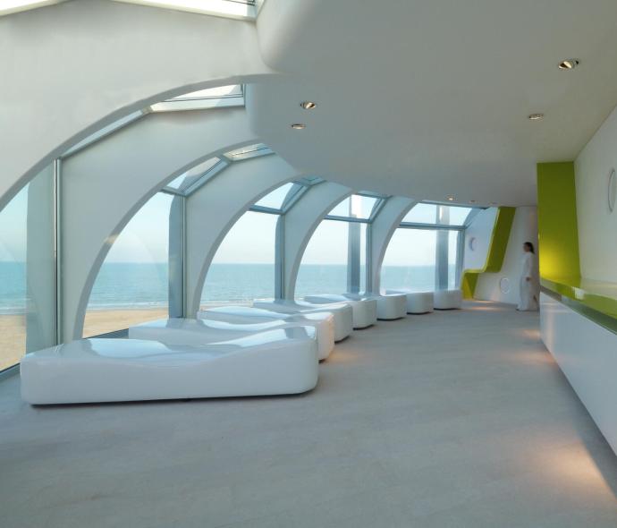 Moderno interno con vista mare, arredi bianchi e dettagli verdi.